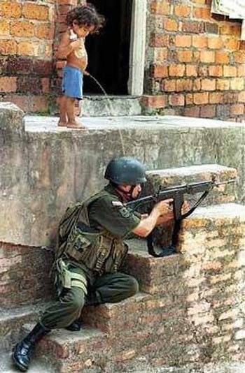 Foto Divertente: Bambino che fa bisogni su elmetto di soldato sottostante