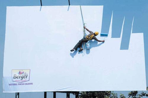 Foto Divertente: Cartellone pubblicitario con uomo che dipinge