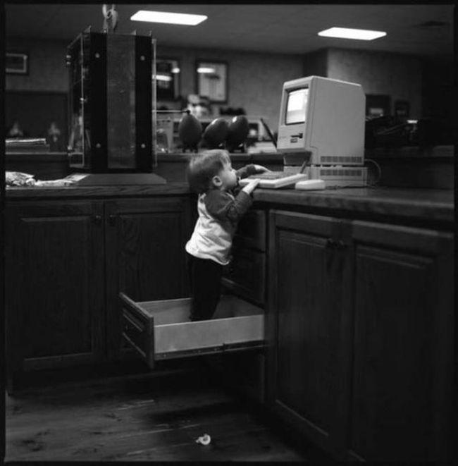 Foto Divertente: Bambino sopra un cassetto che guarda il pc 