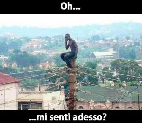 Uomo seduto su palo della luce che parla al telefono