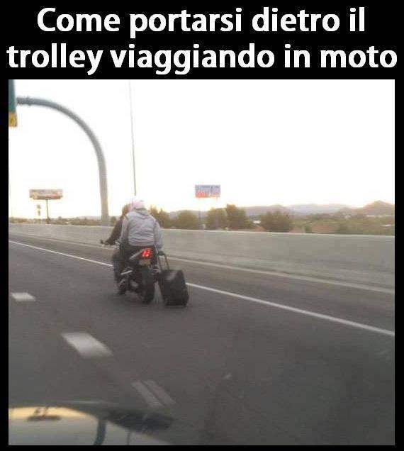 Motociclista che trasporta una valigia a mano