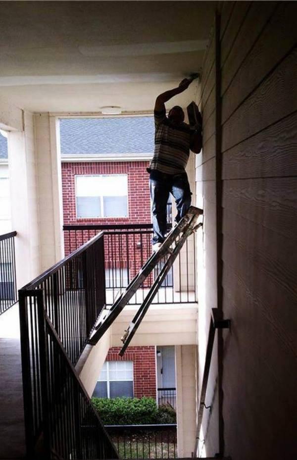 Uomo che tinge una parete con un asse di legno sospeso