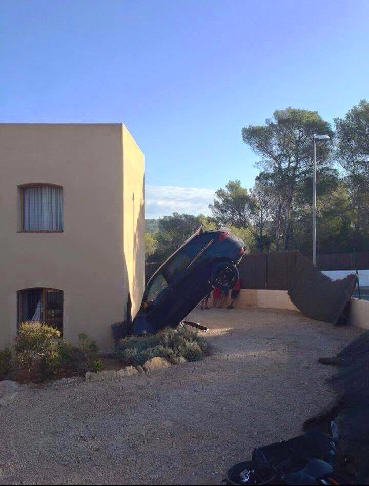 Macchina capovolta e incastrata vicino ad una casa