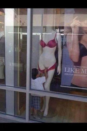 Foto Divertente: Bambino che spoglia un manichino di una vetrina