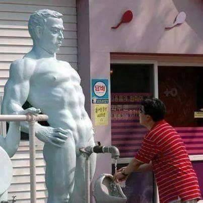 Uomo che si lava le mani ad una fontana con davanti statua nuda