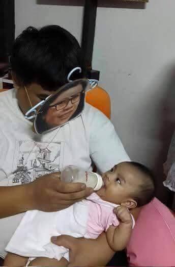 Foto Divertente: Padre che allatta con una maschera somigliante alla madre