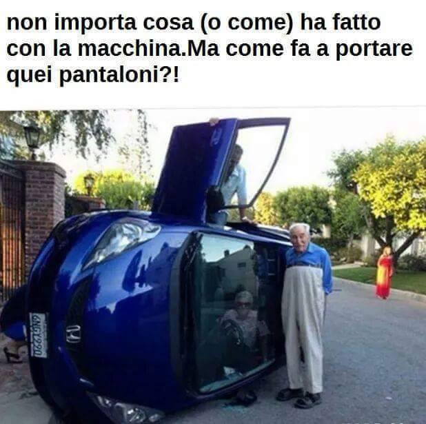 Uomo vicino ad auto ribaltata con i pantaloni ascellari