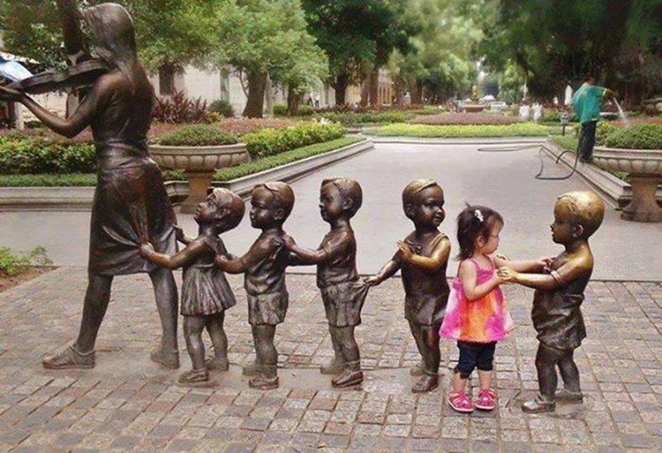 Foto Divertente: Statue di bambini in fila con bambina vera nel centro
