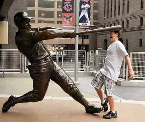 Ragazzo davanti ad una statua di un giocatore da baseball