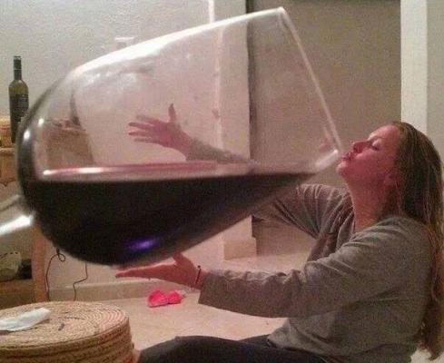 Donna che beve vino da un bicchiere enorme