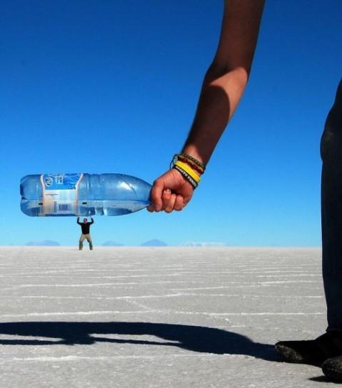 Foto Divertente: Mano che tiene una bottiglia gigante su un piccolo uomo