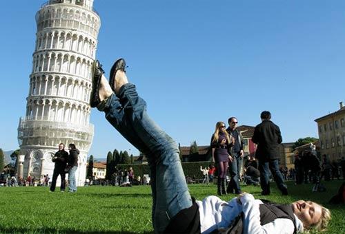 Donna che appoggia i piedi alla torre di Pisa in prospettiva